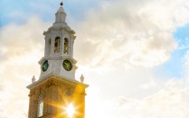 sun shining behind the clock tower on the south campus. 